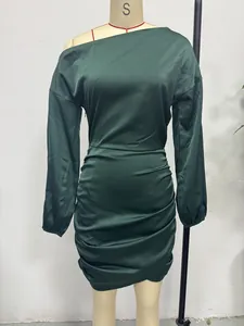Dettaglio di un abito in raso verde scuro monospalla a maniche lunghe