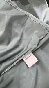 Vue rapprochée de la texture du tissu en satin 100 % polyester et étiquette d'entretien.