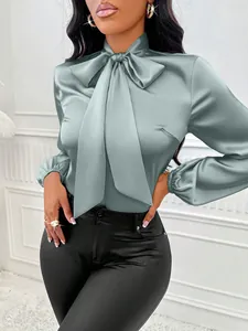 Gros plan d'une élégante blouse en satin vert sauge avec un col à nœud raffiné.