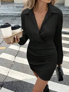 Detail view of a black satin long sleeve mini dress with ruched waist and deep V-neck