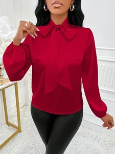 Détail du chemisier en satin rouge avec col à nœud élégant et manches lanternes
