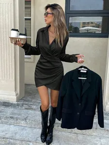 Elegant black satin long sleeve mini dress with pleated waist detail in a street setting