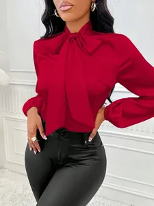 Vue détaillée d'un chemisier chic en satin rouge avec un élégant grand nœud au col.