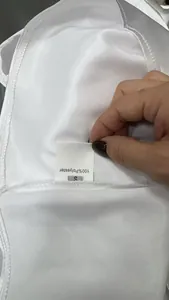 Close-up of wash care label on white satin blouse showing 100% polyester material