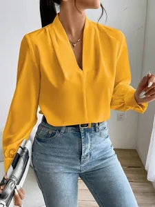 Close-up of a vibrant yellow satin blouse highlighting the V-neck and fabric texture