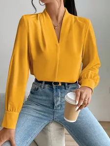 Detail shot of an elegant bright yellow satin blouse with V-neck and lantern sleeves