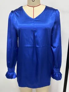 Detail view of royal blue satin blouse with V-neck and ruffled cuffs on mannequin