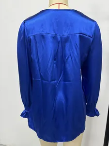 Back view of a vibrant blue long-sleeved satin shirt with pleated detail on a mannequin.