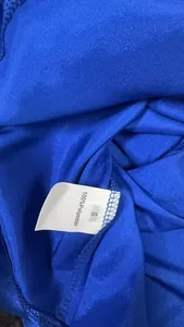 Close-up of blue satin shirt material and care label showing 100% polyester