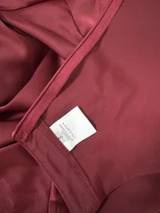 Detail view of burgundy satin jumpsuit with 90% polyester and 10% elastane label