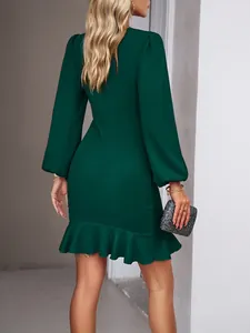 Detail view from the back of a dark green long sleeve dress with ruffled fishtail hem