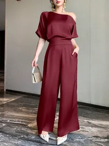 Elegant burgundy satin asymmetric one-shoulder jumpsuit with wide-leg trousers look