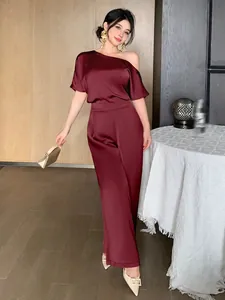Elegant wine red satin asymmetric one shoulder jumpsuit on Asian model in interior