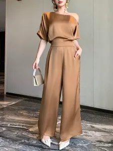 Elegant copper satin one-shoulder jumpsuit set shown on model in luxury interior