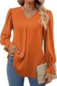 Close-up detail of a vibrant orange satin V-neck blouse featuring elegant smocked flare sleeves