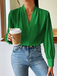 Close-up of an elegant emerald green satin long sleeve blouse featuring a stylish V-neckline