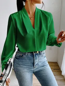 Detail of a green satin V-neck blouse with elegant pleats and long sleeves for women.