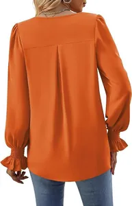 Detailed back view of an orange satin blouse featuring elegant pleats and ruffled cuffs.
