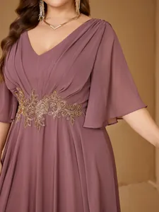 Close-up of an elegant plus size V-neck evening dress featuring gold floral waist embroidery