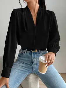 Elegant black satin V-neck blouse detail featuring a smooth sheen and pleated texture.