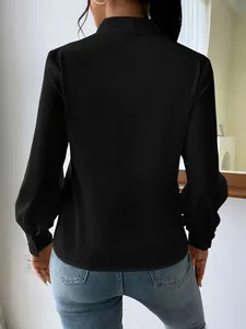 Detail shot of the back of a black satin long sleeve blouse featuring a loose fit design