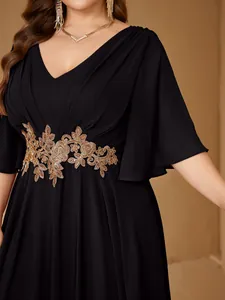Close-up of golden rose embroidery details on black V-neck plus size evening gown dress