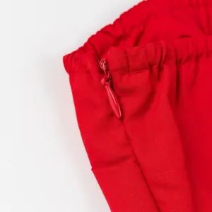 Close-up detail of the red invisible zipper and elastic waist on a vibrant red tube top