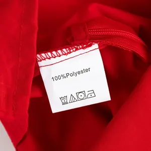 Close-up of clothing care label on red fabric showing 100% polyester material details