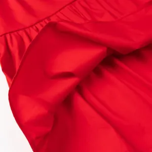 Detailed macro shot of red cotton fabric hem with precise stitching and ruffles