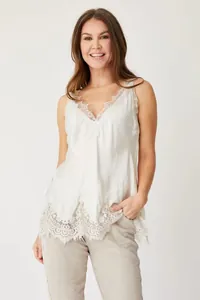 Detail of white V-neck camisole featuring intricate lace patchwork and eyelash trim