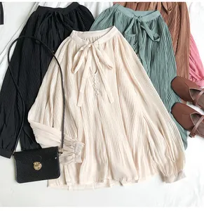Detail view of a vintage pleated chiffon blouse with a V-neck tie and elegant buttons