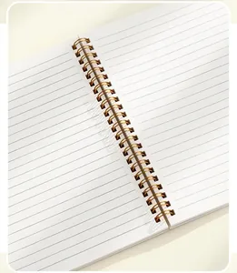 Close-up of A5 spiral notebook featuring gold twin-wire binding and lined pages.