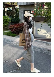 Vue latérale d'une femme enceinte portant une jupe midi en maille grise, style urbain