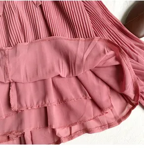 Close-up of pink pleated chiffon blouse showing delicate fabric texture and hem stitching