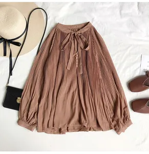 Close-up detail of a vintage brown pleated chiffon blouse with bow-tie neck and V-neckline