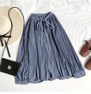 Detail view of a vintage dusty blue pleated chiffon blouse with bow tie neck and props.