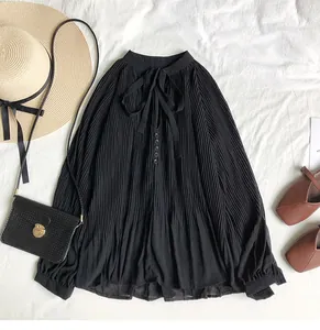 Detail view of black pleated chiffon shirt with vintage tie-neck and button accents.