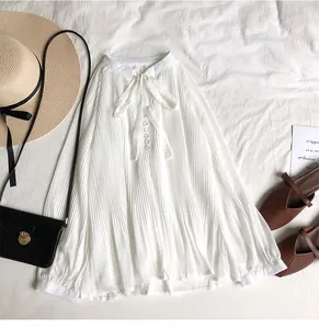 Flat lay of a white pleated chiffon blouse with a V-neck tie bow and stylish accessories
