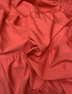 Détail de volants superposés et de la texture du tissu sur une robe d'été corail