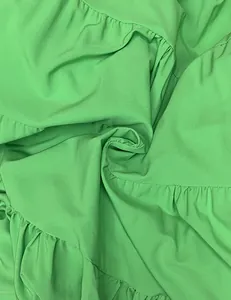 Gros plan sur la texture du tissu vert vif avec des volants sur une robe d'été légère