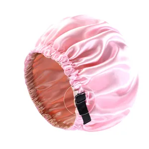Detail der verstellbaren schwarzen Gummischlaufe an einer rosa Satin-Schlafmütze.