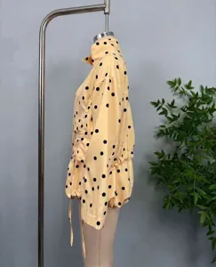 Close-up detail of yellow polka dot jacket featuring side drawstring design and high collar