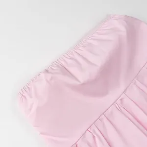 Close-up detail of a pink strapless tube top showing elastic gathered neckline and fine pleats