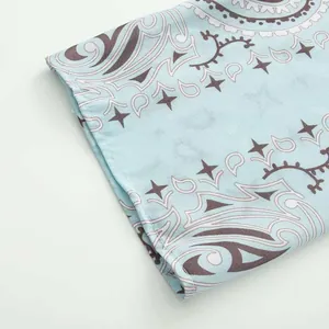 Detail macro view of light blue fabric with dark paisley and star pattern prints.