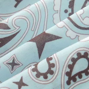 Macro detail of light lake blue fabric with dark brown paisley and star print patterns