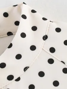 Close-up of elegant black polka dot print and fine stitching on white blouse collar