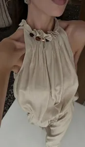 Dettaglio del top a lupetto beige con volant di perline e pantaloni coordinati.