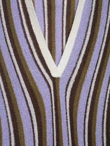 Close-up of the textured vertical stripes and V-neck of a purple and brown knitted dress