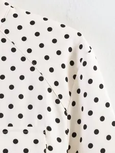 Close-up detail of white and black polka dot fabric showing stitching on the shoulder seam