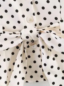 Close-up detail of a white polka dot printed top with a matching waist tie belt